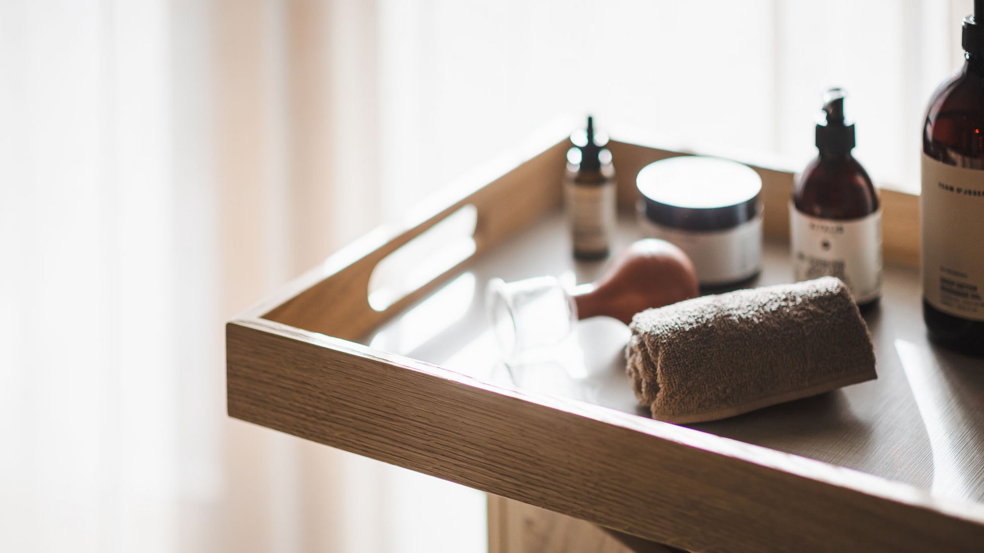 Molto più di una sauna in Val Pusteria: l’Alpenreych Spa Vassoio in legno con asciugamano, teli e bottiglie cosmetiche sotto luce morbida