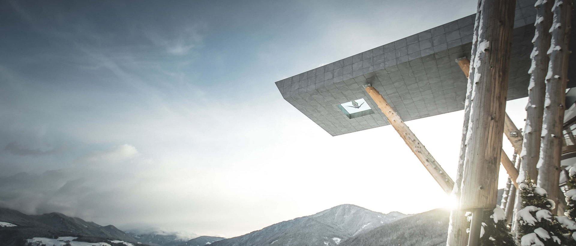 Il nostro hotel con infinity pool in Alto Adige: una meraviglia Montagne innevate con edificio moderno e sole che sorge nella valle