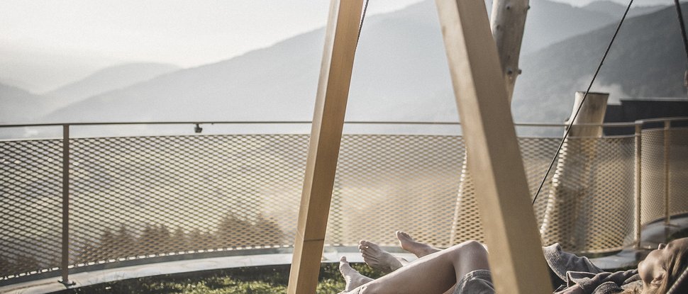 Aktuelle News und Geschichten aus Olang Person entspannt auf einer Hängematte mit Bergblick bei Sonnenuntergang