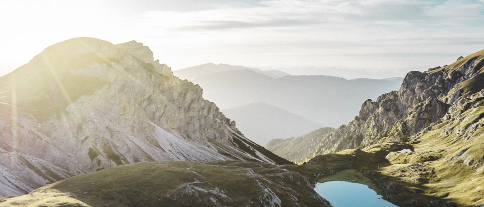 Aktuelle News und Geschichten aus Olang Sonnenaufgang über bergigem Gebiet mit klarem See in der Mitte