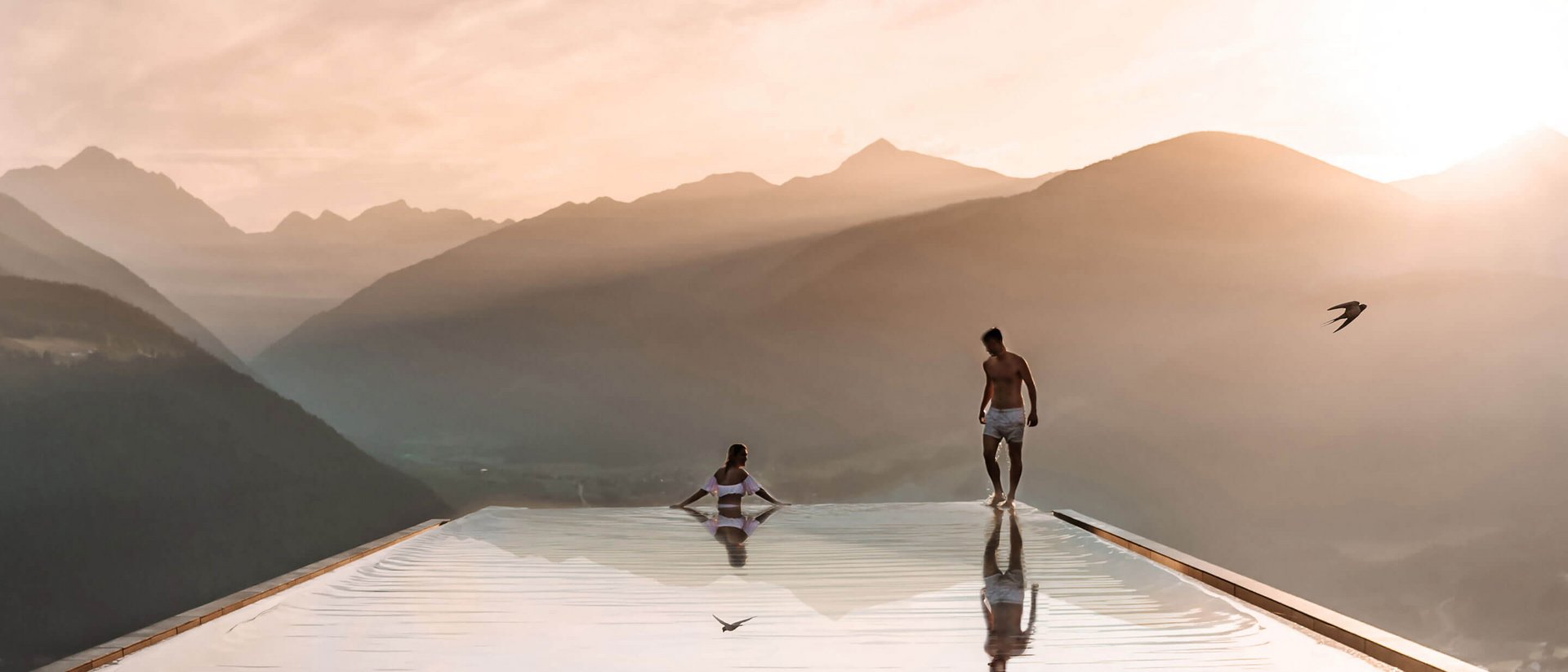 Unser Sky Pool in Südtirol, ein Prachtexemplar Zwei Personen an einem Infinity-Pool mit Bergblick bei Sonnenuntergang