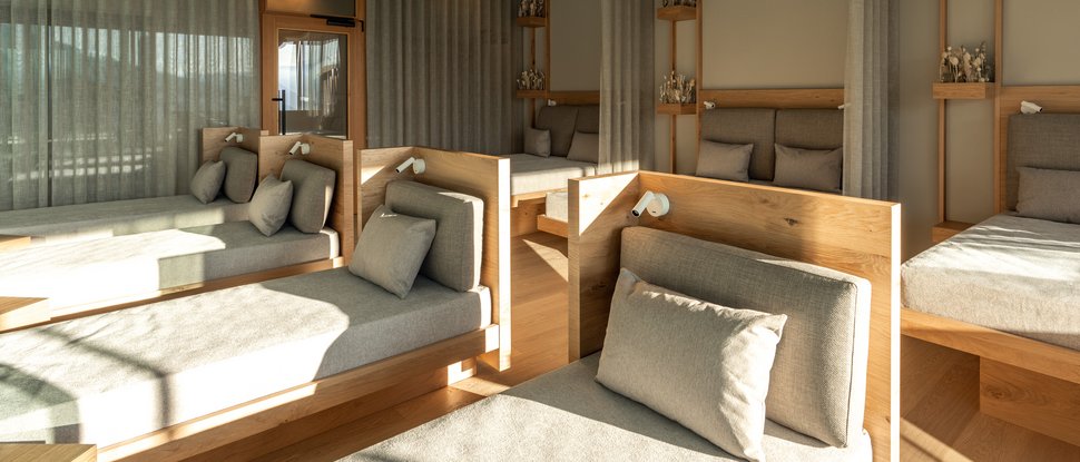 Il nostro hotel a Valdaora tra cielo e terra Sala relax moderna con lettini comodi e decorazioni in legno alla luce naturale