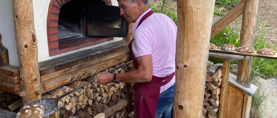Aktuelle News und Geschichten aus Olang Mann backt Brot in einem Holzofen im Freien