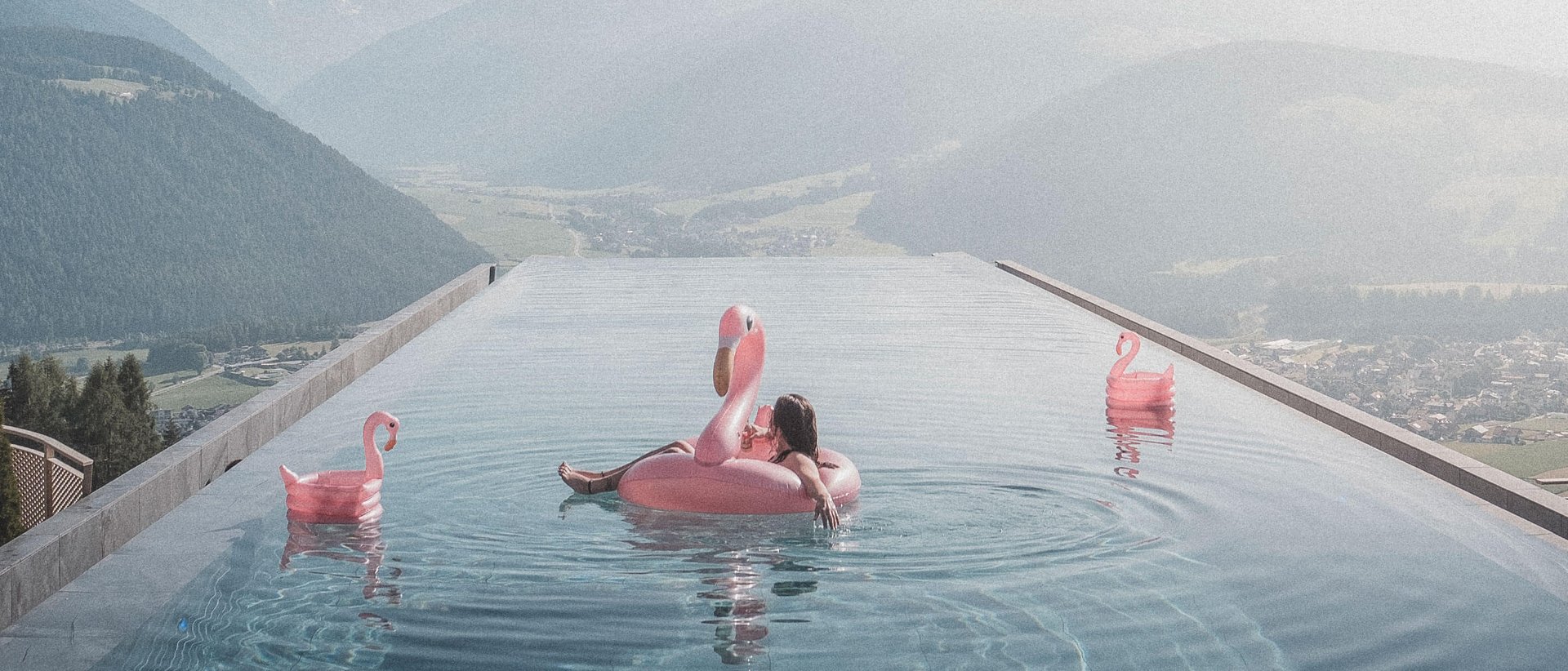 Unser Sky Pool in Südtirol, ein Prachtexemplar Person auf Flamingo-Schwimmring im Infinity-Pool mit Bergblick