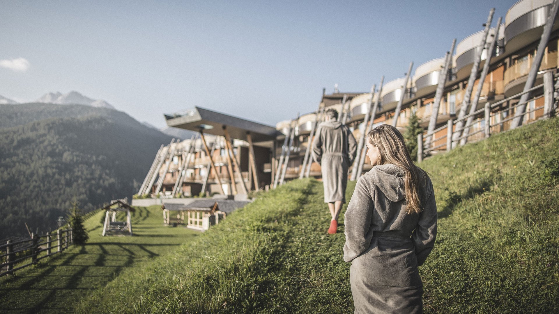 Unsere Parks, Ihre Rückzugsorte Zwei Personen in Bademänteln gehen an einem Berghotel im Grünen entlang