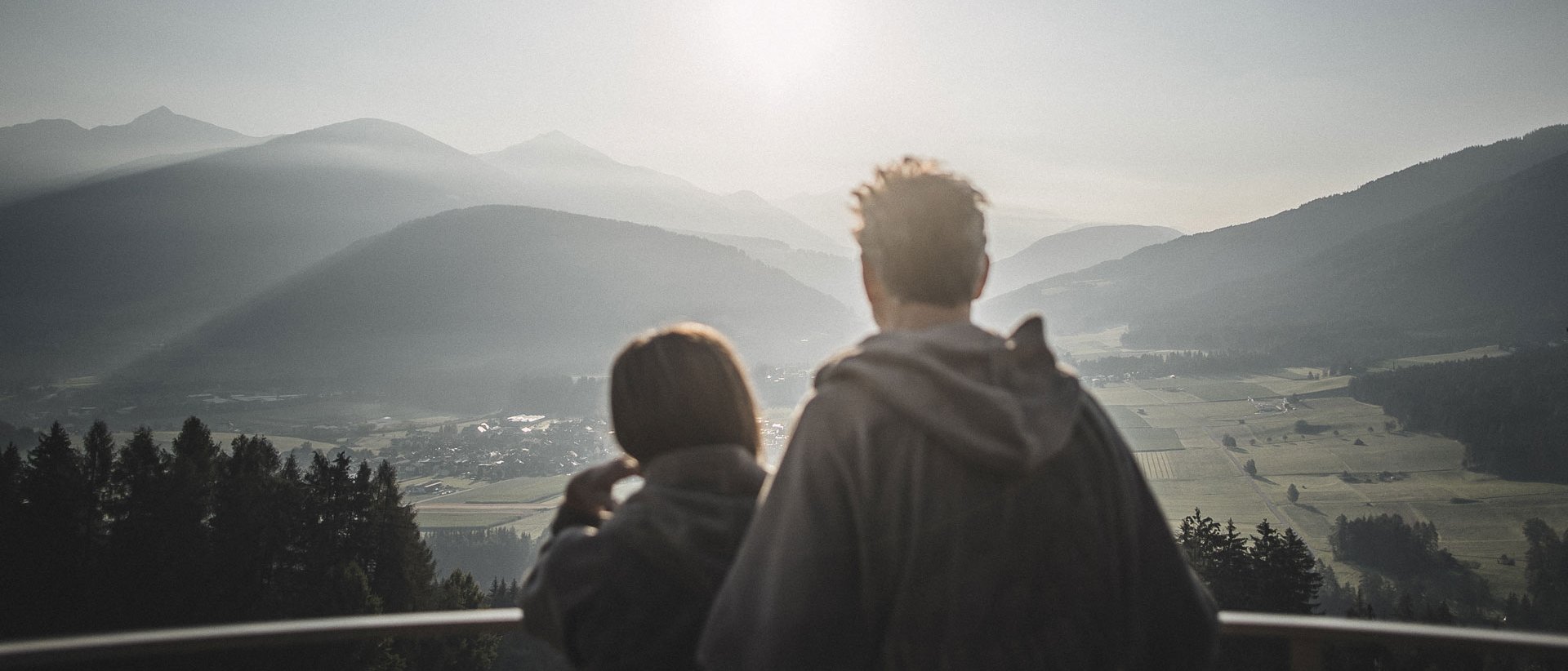 Hotel im Pustertal mit 5 Sternen Paar blickt auf neblige Berglandschaft bei Sonnenaufgang