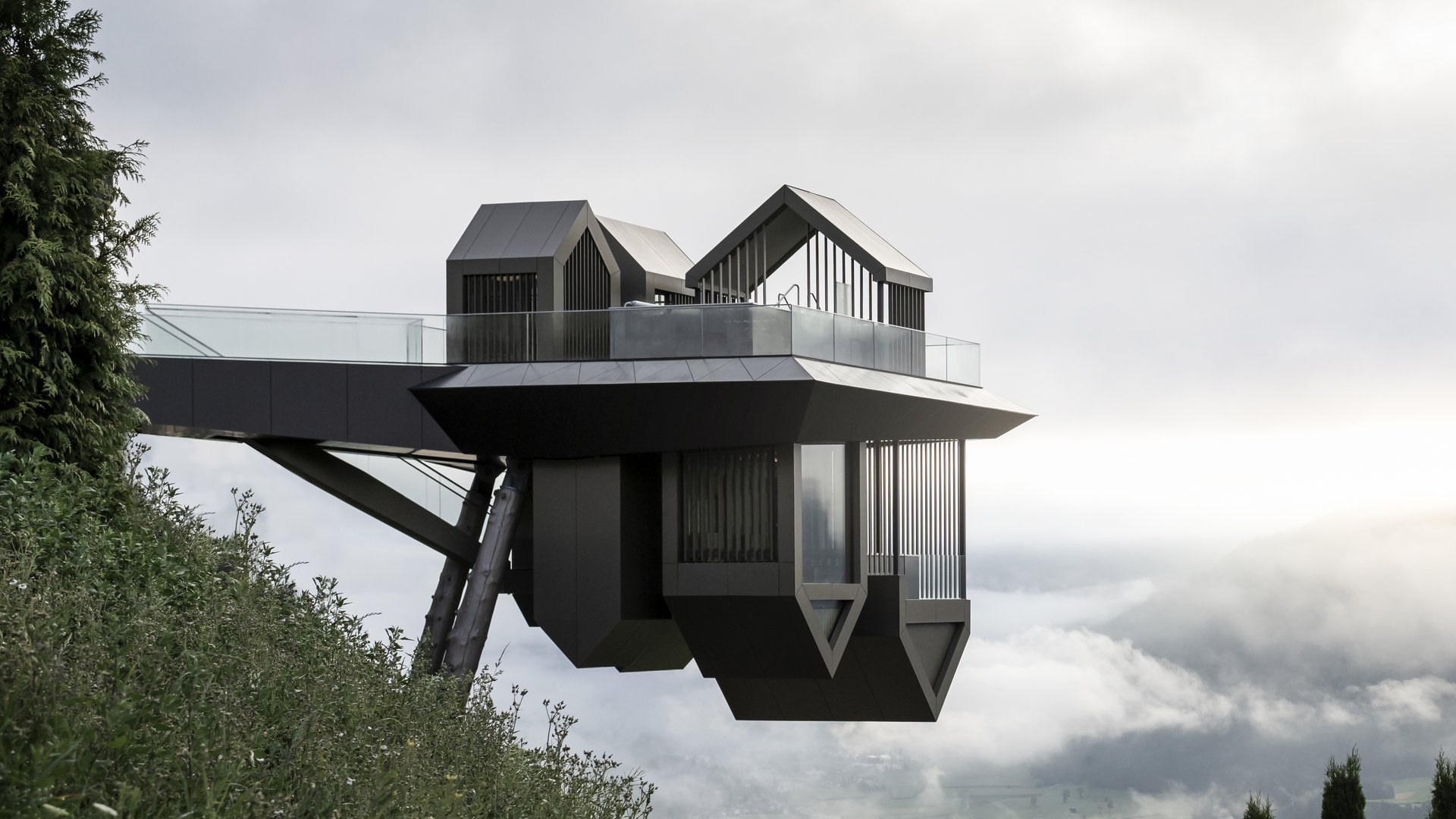 Il nostro hotel con infinity pool in Alto Adige: una meraviglia Punto di osservazione moderno su pilastri con vista sulla valle nebbiosa e le montagne