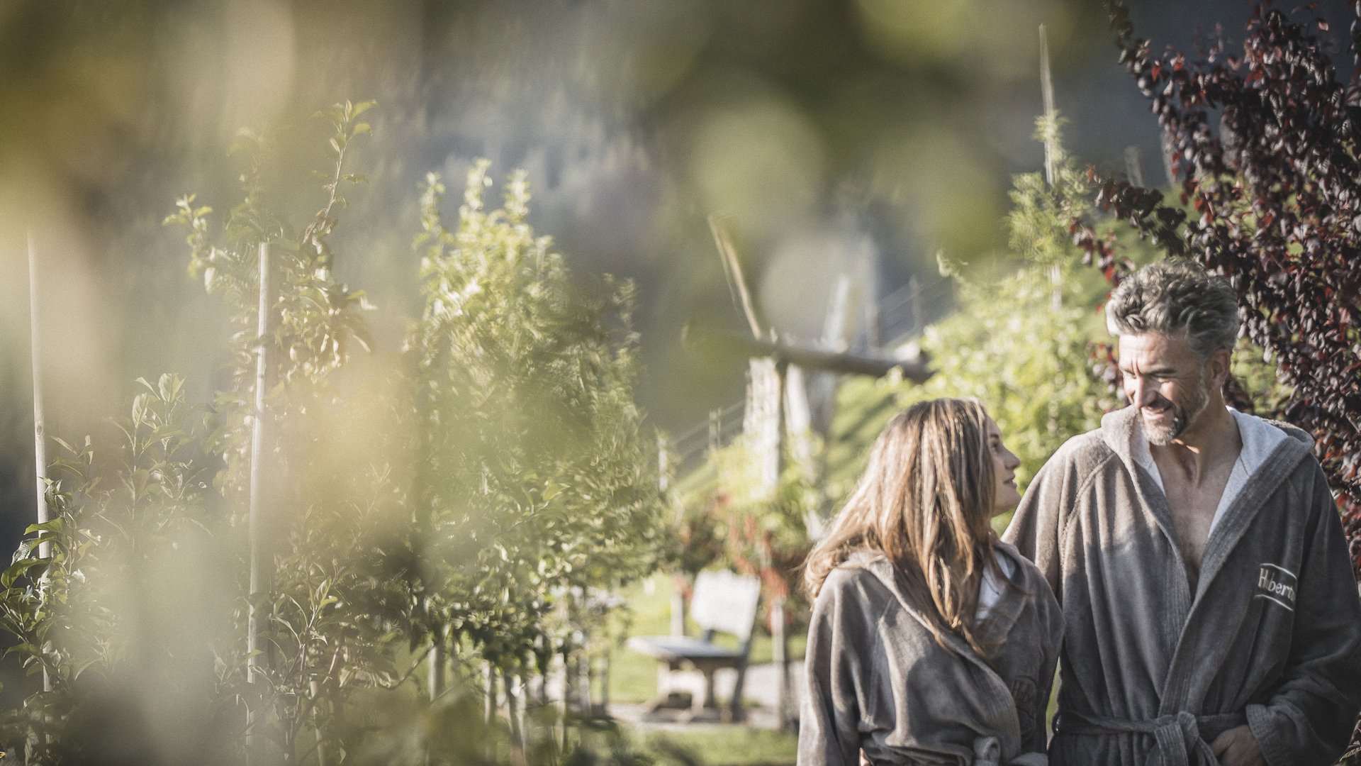 Unsere Parks, Ihre Rückzugsorte Paar in Bademänteln spaziert draußen im Garten an sonnigem Tag