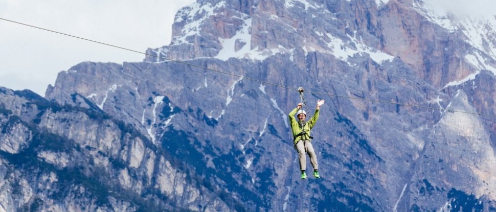 Aktuelle News und Geschichten aus Olang Person fährt mit einem Seilrutschen vor schneebedeckten Bergen