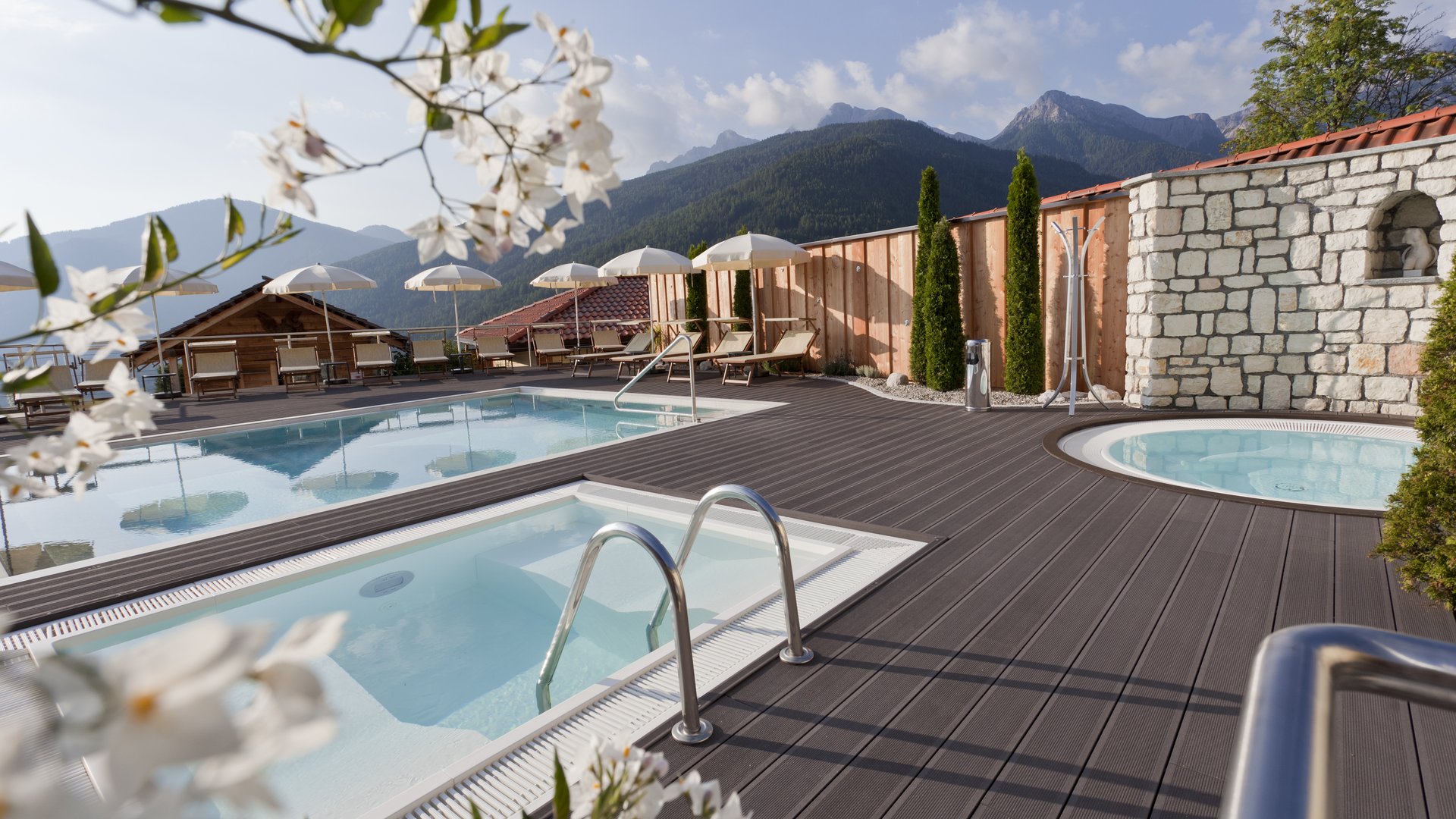 Unser Sky Pool in Südtirol, ein Prachtexemplar Außenpool mit Liegestühlen und Bergblick an einem sonnigen Tag