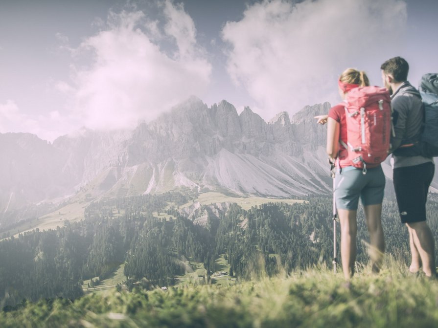 Unser Hotel in Olang zwischen Himmel und Erde Zwei Wanderer blicken auf bewaldete Berge und Wolken