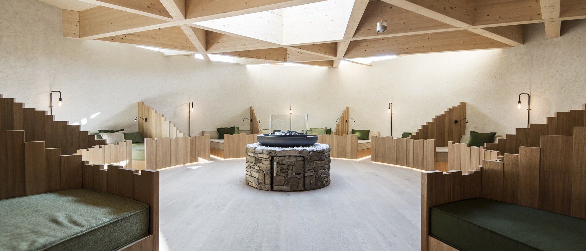 Das Wellnesshotel im Pustertal zum Entspannen Moderner gemütlicher Sitzbereich mit Holzbänken und zentralem Steintisch unter Holzdeckenfenster