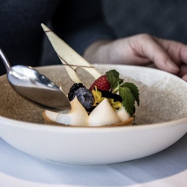 Ein einzigartiges, individuelles und unvergessliches Erlebnis in den Bergen. Feines Dessert mit Beeren und Sahne in weißem Teller
