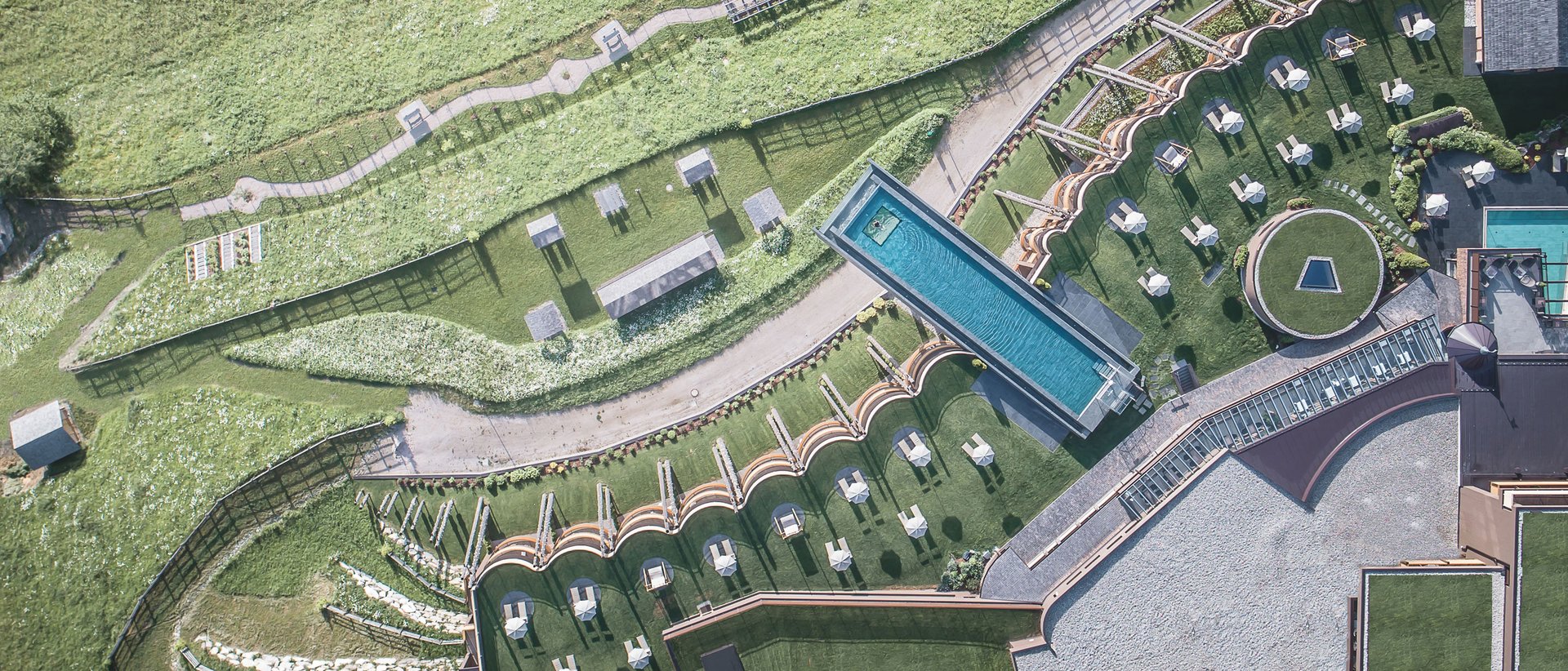 Unser Hotel in Olang zwischen Himmel und Erde Luftaufnahme eines modernen Hotels mit Pool und grüner Landschaft