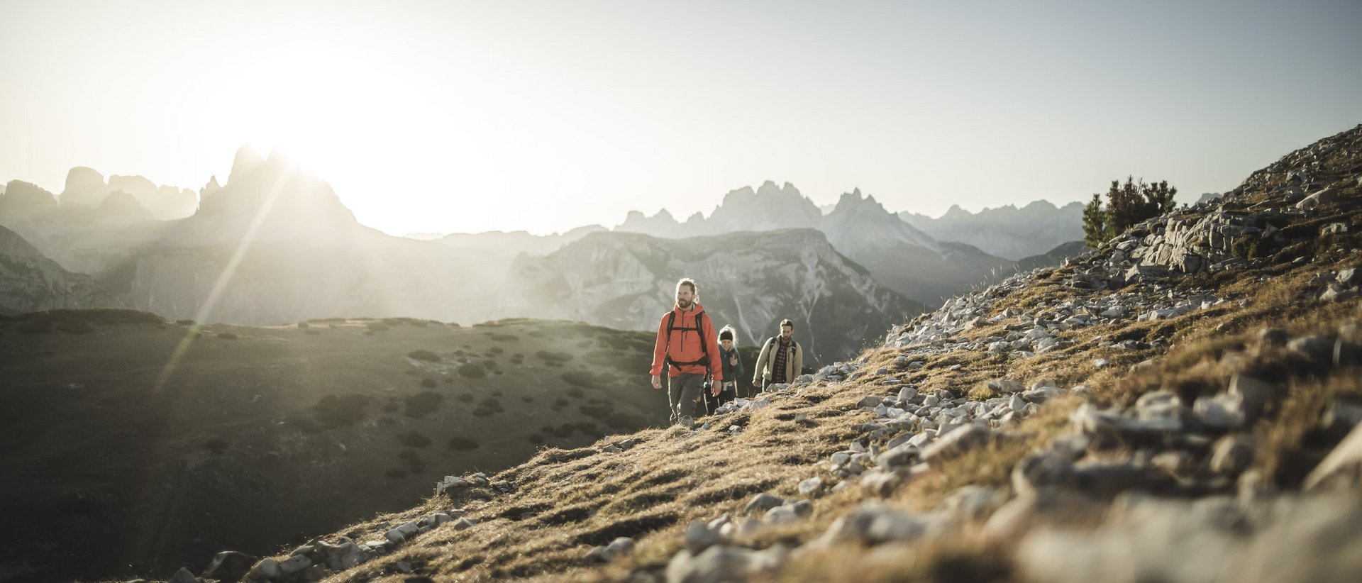 Aktivurlaub in Südtirol: ein Erlebnis Drei Wanderer steigen bei Sonnenaufgang in den Bergen auf