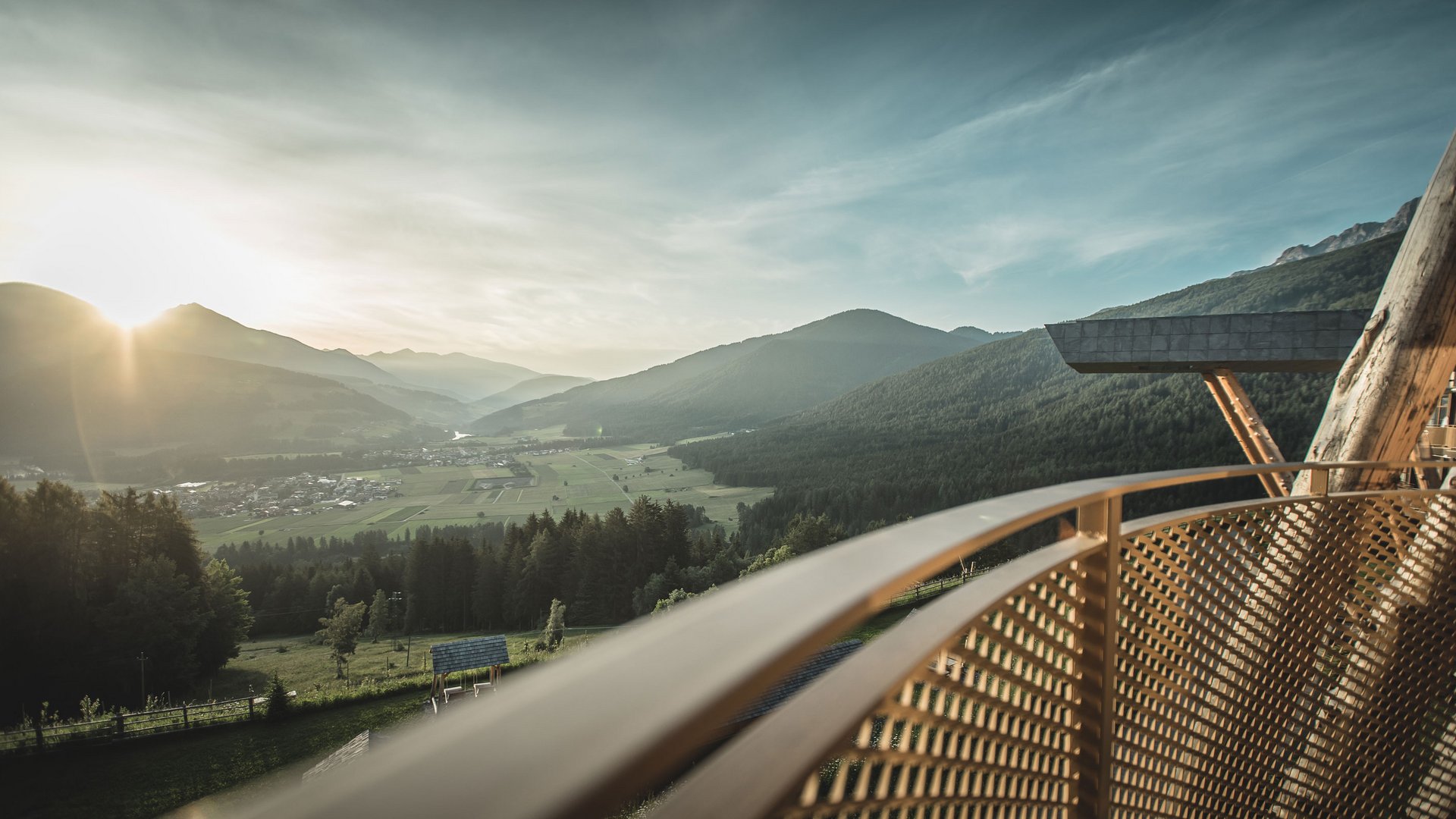 Unser Hotel in Olang zwischen Himmel und Erde Sonnenuntergang über einem Tal mit Bergen und Blick vom Balkon mit Metallgeländer