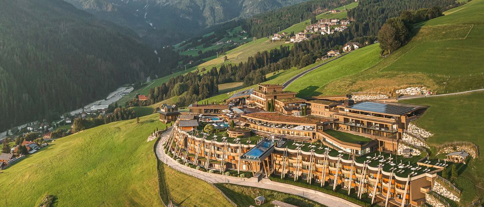 Unser Hotel in Olang zwischen Himmel und Erde Luxushotel auf grüner Bergwiese vor den Alpen bei klarem Himmel