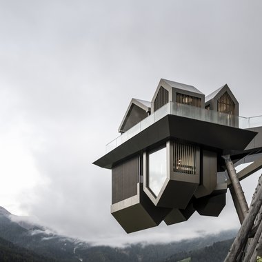 Awards & Press Modernes Architekturgebäude auf Stelzen mit Bergblick und bewölktem Himmel
