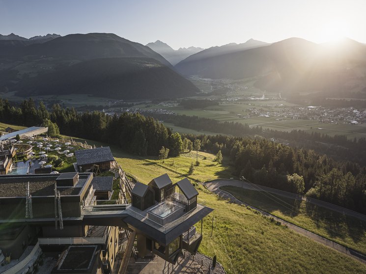 Heaven & Hell, i nostri nuovi highlight Panorama montano con edificio moderno e sole che sorge in valle