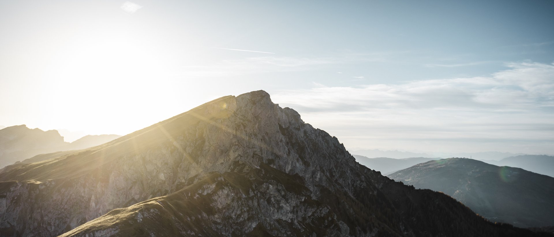 Aktivurlaub in Südtirol: ein Erlebnis Sonnenaufgang über felsigen Berggipfeln mit blauem Himmel