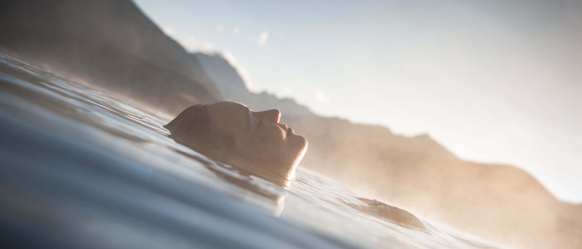 Unser Sky Pool in Südtirol, ein Prachtexemplar Person entspannt schwebend im Wasser mit Berglandschaft im Hintergrund