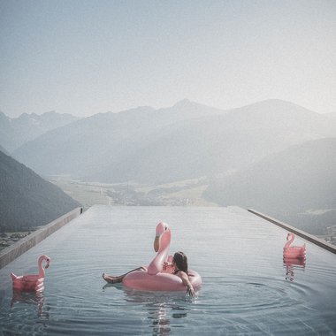 Unsere Parks, Ihre Rückzugsorte Entspannter Mensch auf Flamingo-Schwimmring im Infinity-Pool mit Bergblick