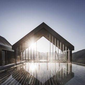 Das Wellnesshotel im Pustertal zum Entspannen Moderne Hoteldachterrasse mit Pool bei Sonnenaufgang in den Bergen