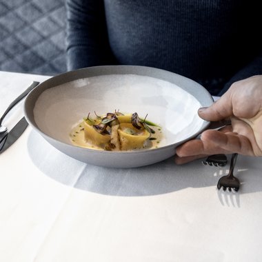 Our weekly programme in summer Woman being served plate with fine pasta and mushrooms at restaurant