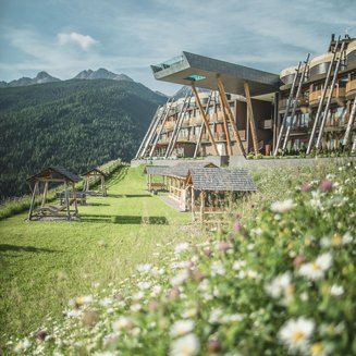 Unsere Parks, Ihre Rückzugsorte Modernes Hotel mit Garten und Blumen vor einer Bergkulisse