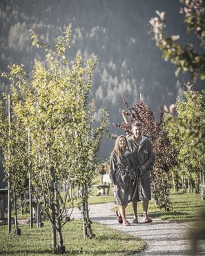Unsere Parks, Ihre Rückzugsorte Paar in Bademänteln geht auf einem Baumweg im Freien spazieren
