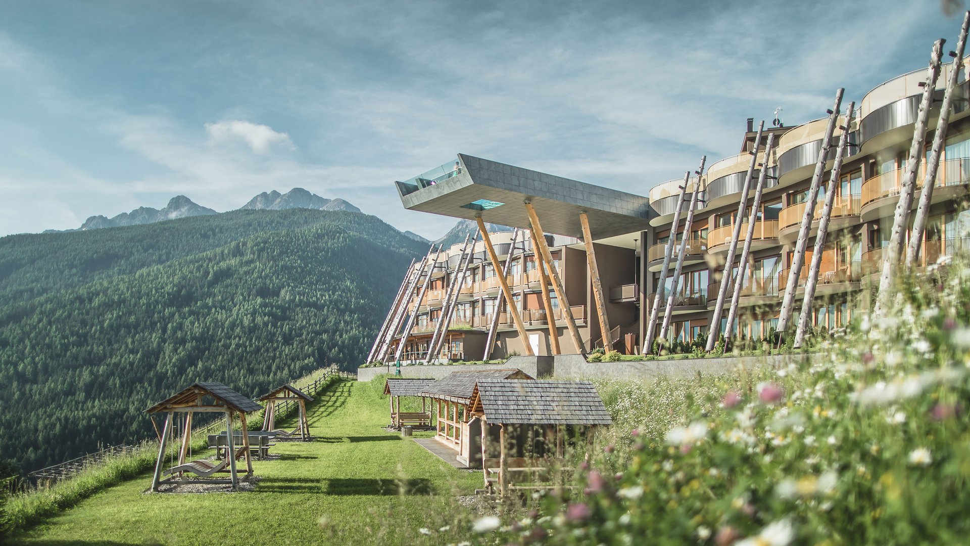 Unser Hotelgutschein: Südtirol im Geschenkformat Modernes Hotel mit Aussichtsplattform in den Bergen und Blumenwiese